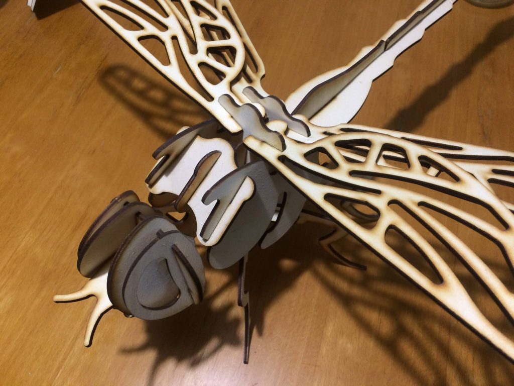 A laser cut dragonfly, with laser cutting burn marks intentionally left on